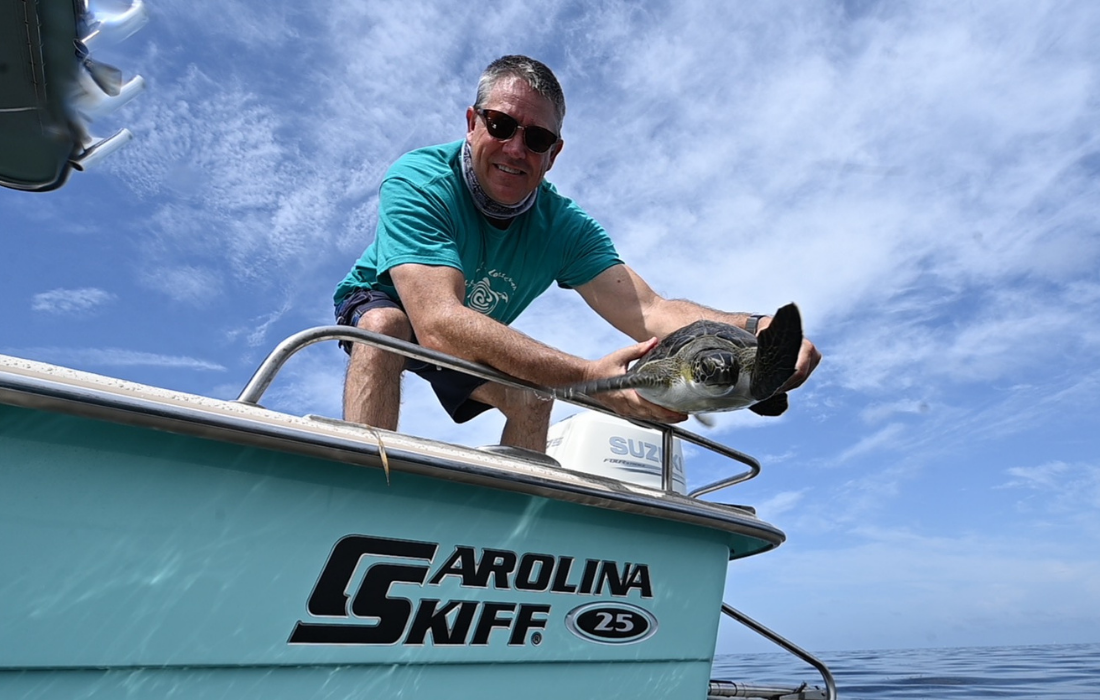 Expert handling sea turtle on Carolina Skiff boat